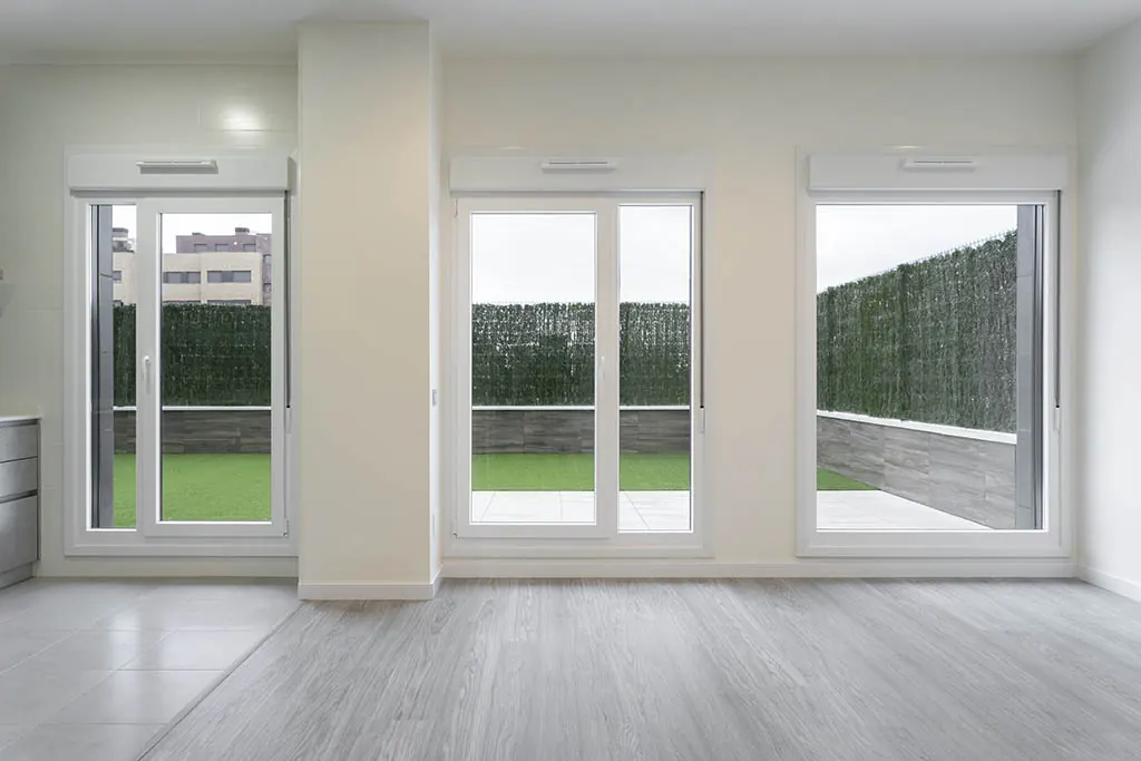 Interior con balconeras blancas de PVC abiertas a un jardín
