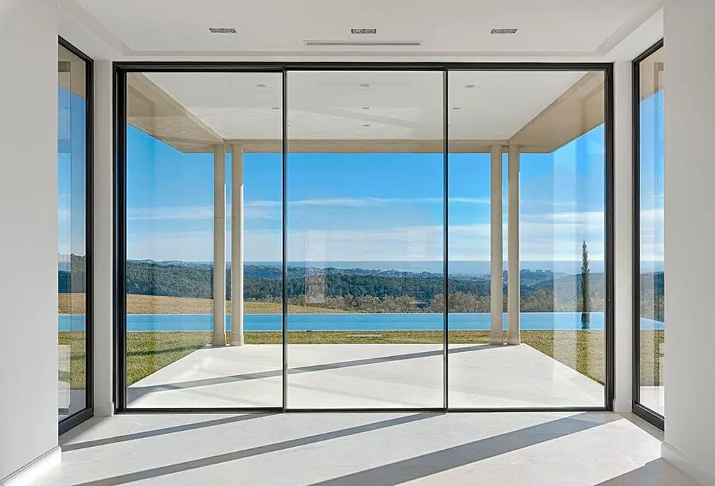 Salón con una gran corredera de aluminio negra abierta a las vistas