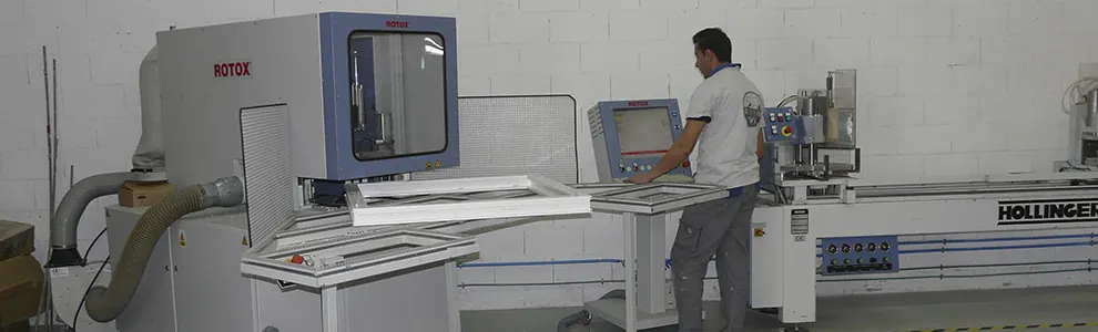 Operario de Koryak ante la soldadora de perfiles de PVC, con marcos de ventana recién soldados